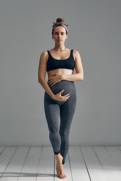 Ładny brzuch w ciąży na szarym tle Widok z boku młodej kobiety w ciąży, obejmując jej brzuch rękami Duży brzuch w trzecim trymestrze ciąży zbliżenie Koncepcja życia w ciąży