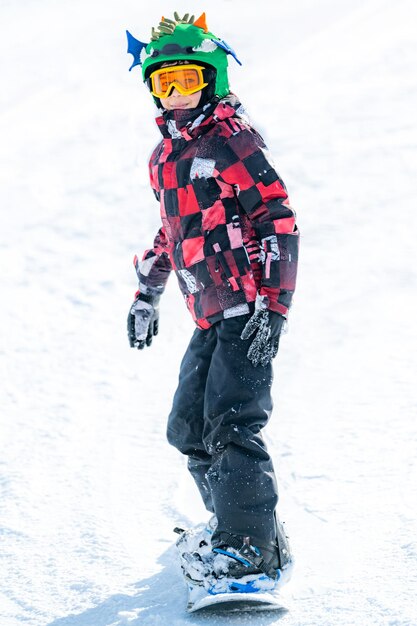 Ładny chłopak zabawy na snowboardzie w górach
