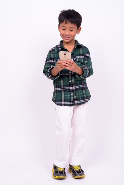 ładny chłopiec azjatyckich sobie zieloną koszulę w kratkę na białej ścianie