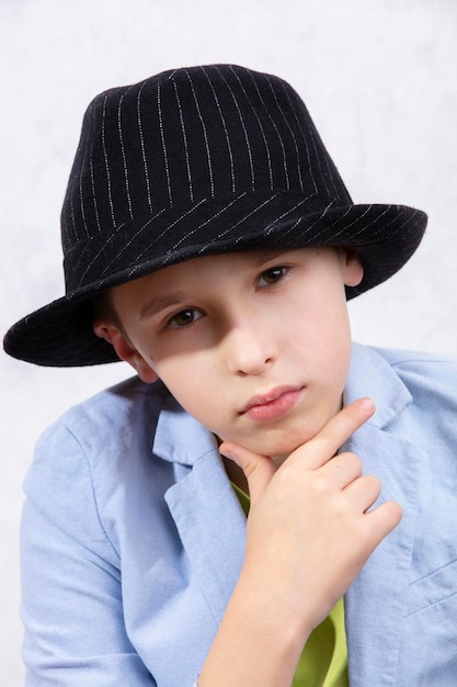 Zdjęcie Ładny, elegancki chłopiec w eleganckim kapeluszu patrzy rozmyślnie w kamerę.