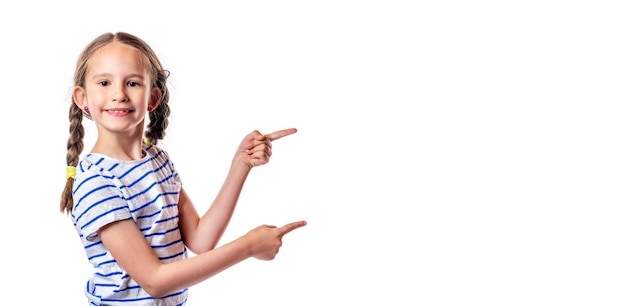 Zdjęcie Ładny europejskiej uśmiechnięta dziewczynka z warkoczykami wskazującymi palcami na białym tle. wolne miejsce na twój tekst. koncepcja marketingu i reklamy.