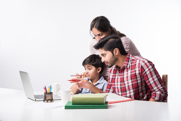 Ładny Indyjski Chłopiec Z Ojcem I Matką Studiuje Lub Odrabia Pracę Domową W Domu Za Pomocą Laptopa I Książek - Koncepcja Edukacji Onlineing