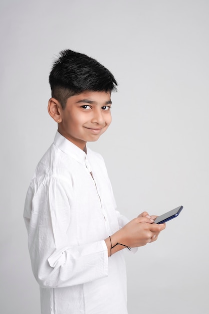 Ładny indyjski mały chłopiec za pomocą inteligentnego telefonu