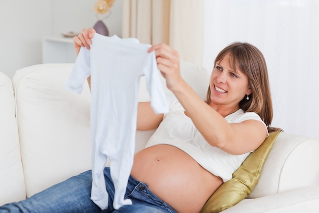 Ładny kobieta w ciąży trzyma dziecka r podczas gdy kłamający na kanapie