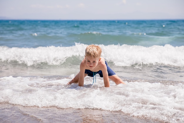 Ładny mały chłopiec bawi się na plaży nad morzem jest szczęśliwy Koncepcja letnie wakacje odpoczynku zabawy