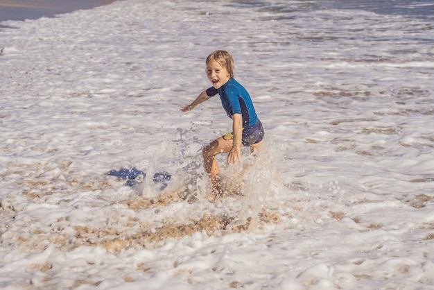 Ładny mały chłopiec bawi się na tropikalnej plaży podczas letnich wakacji