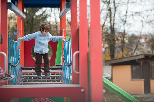 ładny mały chłopiec bawiący się w parku zabaw w pochmurny jesienny dzień