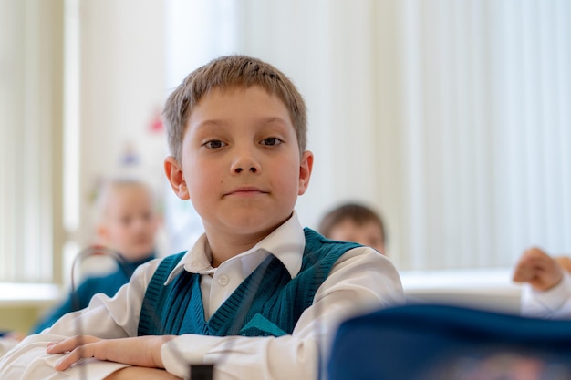 Ładny mały chłopiec siedzi w klasie w szkole