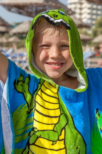 Ładny mały chłopiec sobie zabawny ręcznik na plaży