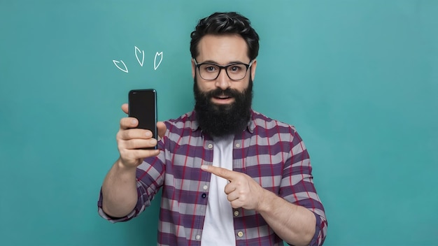 Ładny mężczyzna z brodą rozmawia z tobą i wskazuje na wyświetlacz smartfona, uśmiechając się i mówiąc swoje zdanie.