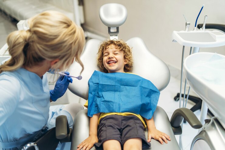 Ładny młody chłopak odwiedza dentystę, po sprawdzeniu zębów przez kobietę dentystę w gabinecie stomatologicznym.