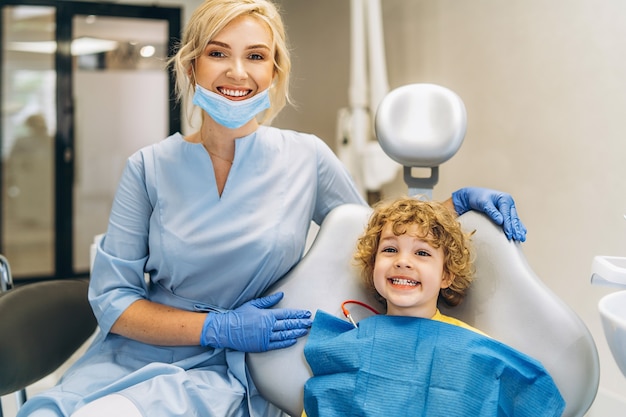 Ładny młody chłopak odwiedzający dentystę i sprawdzający jego zęby przez dentystę w gabinecie stomatologicznym