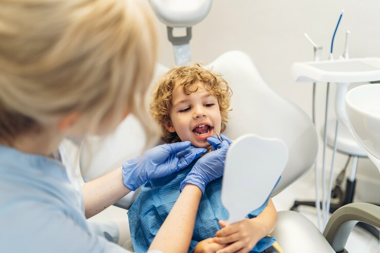 Ładny młody chłopak odwiedzający dentystę i sprawdzający jego zęby przez dentystę w gabinecie stomatologicznym