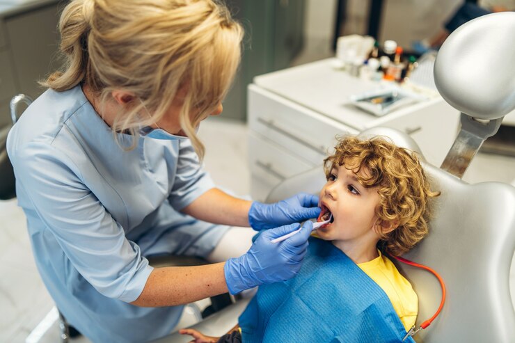 Ładny młody chłopak odwiedzający dentystę, po sprawdzeniu zębów przez kobietę dentystę w gabinecie stomatologicznym.