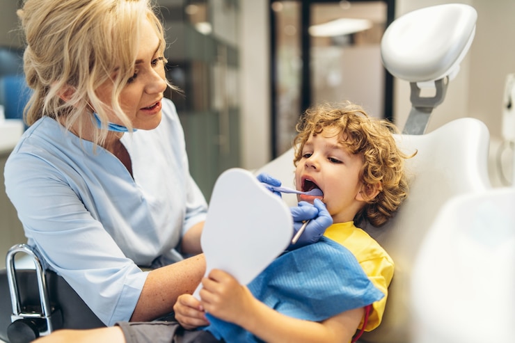 Zdjęcie ładny młody chłopak odwiedzający dentystę, po sprawdzeniu zębów przez kobietę dentystę w gabinecie stomatologicznym.