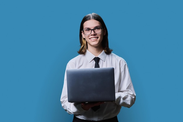 Ładny młody mężczyzna używający laptopa na jasnym tle studia