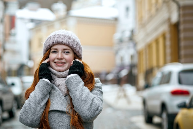 Ładny rudowłosy kobieta nosi ciepłe zimowe ubrania idąc ulicą. Miejsce na tekst