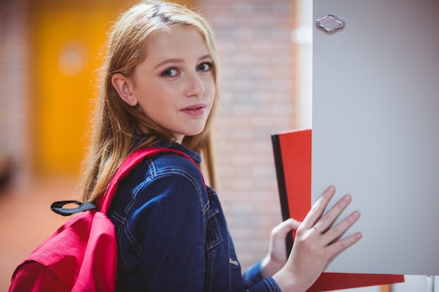 Zdjęcie Ładny uczeń z plecaka kładzenia notatnikiem w szafce