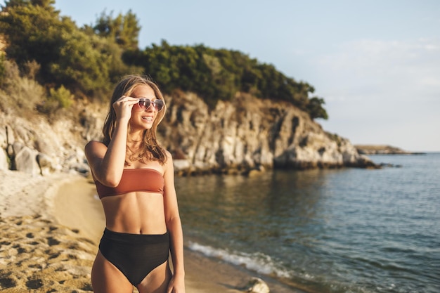 Ładny uśmiechający się dziewczyna z okularami przeciwsłonecznymi w kształcie serca, ciesząc się letnimi wakacjami na plaży.