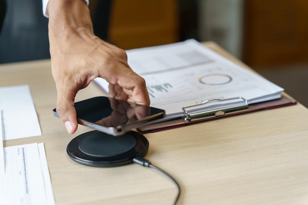 Ładowanie baterii telefonu komórkowego za pomocą bezprzewodowego urządzenia ładującego na stole Ładowanie smartfona na podkładce ładującej Telefon komórkowy w pobliżu ładowarki bezprzewodowej Koncepcja nowoczesnej technologii stylu życia