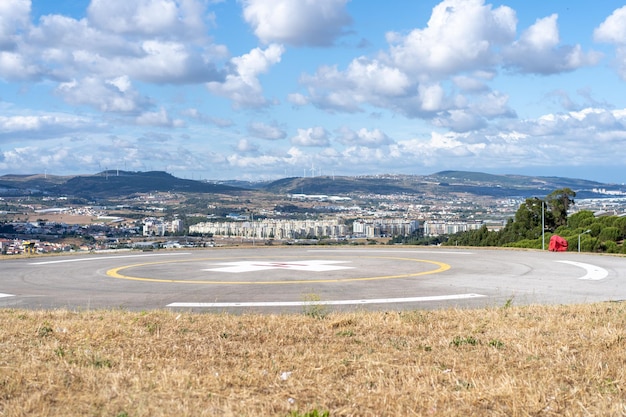 Lądowisko dla helikoptera w pobliżu szpitala ratunkowego w Portugalii z chmurowym niebem i miastem w tle