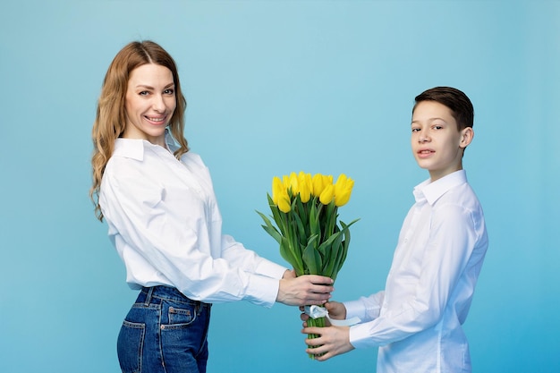 Łagodny syn gratuluje szczęśliwej mamie i daje jej bukiet tulipanów z gratulacjami
