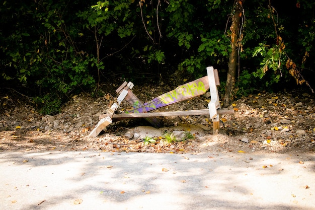 Łamana ławka z graffiti na nim oprócz drogi w lesie