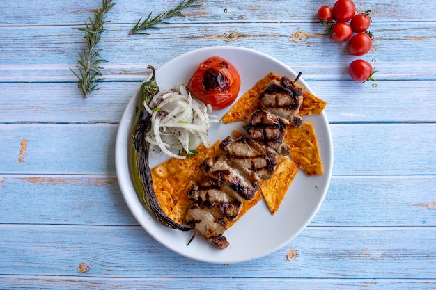 Lamb Delight grillowana na niebieskim tle drewna z pieczonymi pomidorami, cebulą i papryką