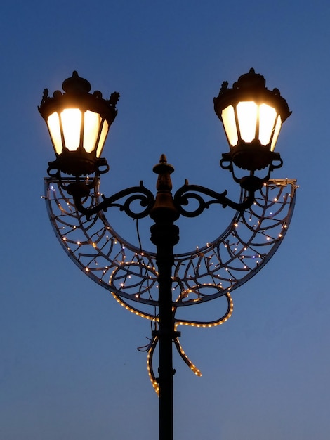 Lampa uliczna z dekoracją świąteczną na tle błękitnego nieba