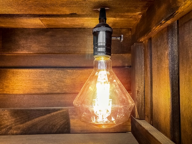 Lampa wisząca retro z zabytkową żarówką na drewnianym tle