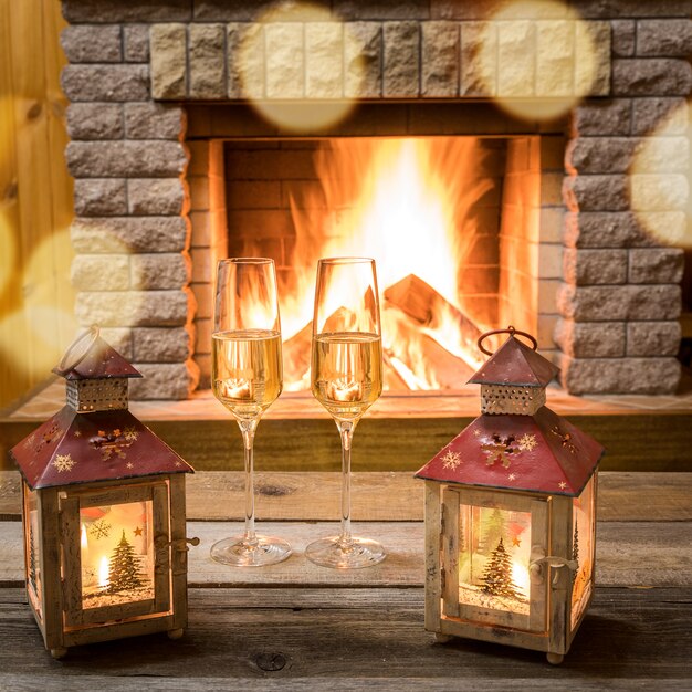 Lampiony świąteczne i kieliszki do szampana przy kominku, w wiejskim domu.