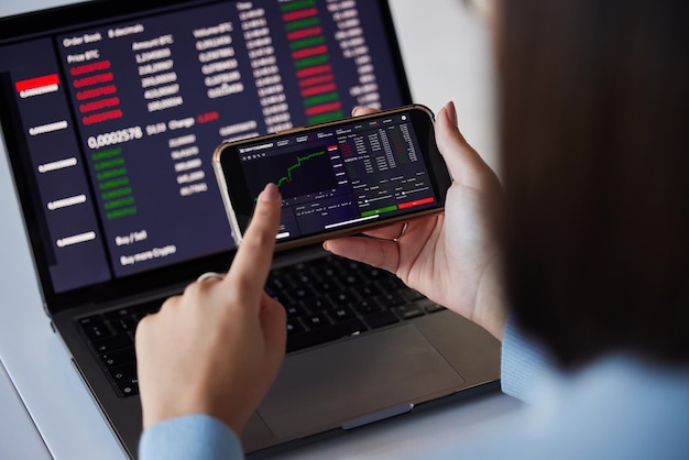 Laptop i telefon z wykresem giełdowym w rękach kobiety do analizy danych kryptograficznych i ekranu bitcoin Rozwój e-commerce Fintech i dziewczyna w technologii dla zysków i inwestycji w statystyki finansowe