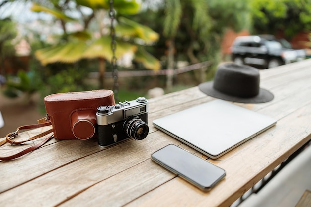 Laptop kapelusz telefon i aparat fotograficzny na drewnianym stole