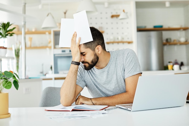 Zdjęcie laptop mężczyzna komputer domowy zmęczony młody ból głowy badanie problemu biznesowego zmartwiony czytanie stresu
