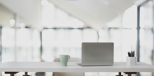 Laptop na biel stole i filiżance kawy w nowożytnym biurze