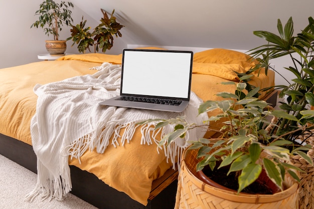 Zdjęcie laptop na łóżku i zielone rośliny
