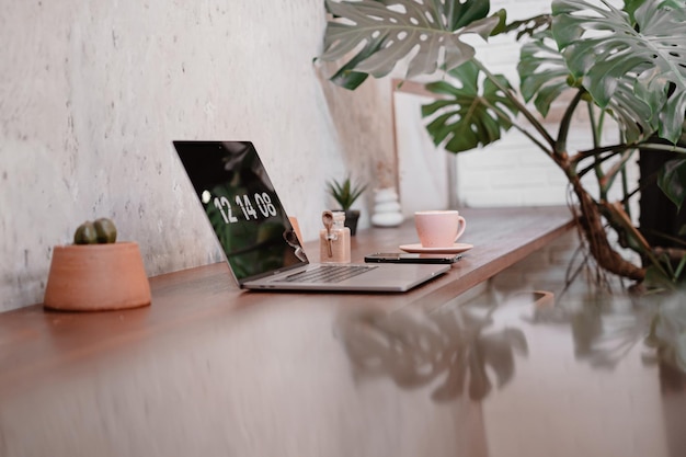 Laptop na stole z filiżanką kawy z kaktusem i liściem monstera w kawiarni