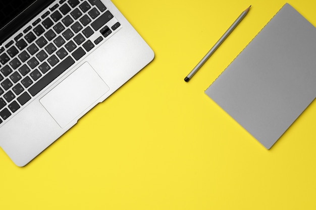 Laptop, notatnik i ołówek na żółto