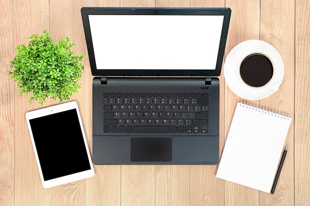 Laptop, tablet cyfrowy, notatnik, roślina doniczkowa, kawa i długopis na drewnianym stole