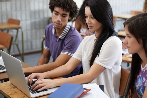 Laptop uniwersytecki i studenci przy biurku razem dla rozwoju w testach uczenia się i przyszłych możliwościach Edukacja mężczyzna i kobieta z internetowym projektem grupy badawczej i studiowanie do egzaminu online