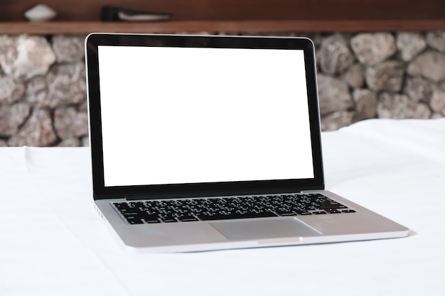 Zdjęcie laptop z białym ekranem makieta na białym łóżku.