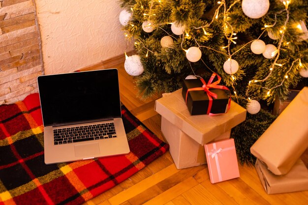 Laptop Z Białym Pustym Pustym Ekranem Makiety Z Prezentami Prezentami, Ozdobione Choinką W Tle Santa House. Reklamy Dostawy Zakupów Online W Witrynie E-commerce.