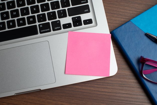 Laptop z różowym nutowym kijem i notatnikiem z czarnym piórem