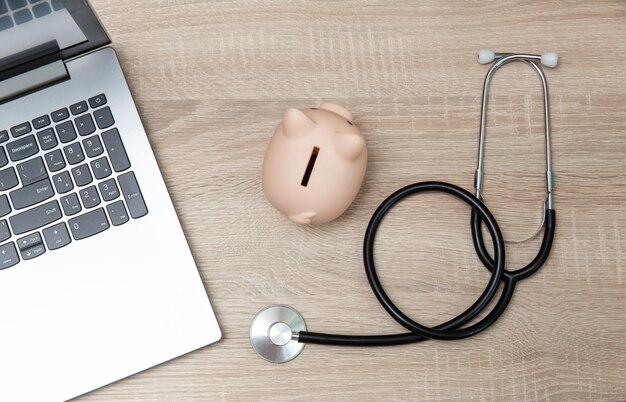 Zdjęcie laptop z skarbnikiem i stetoskopem na drewnianym stole
