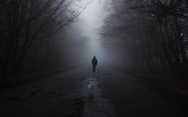 Las we mgle. mężczyzna idzie we mgle. Ciemny mglisty las z magiczną atmosferą