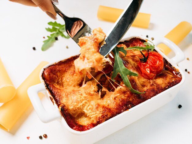 Lasagne porcja białe tło koncepcja włoskiej żywności. tłuste pyszne niezdrowe jedzenie.