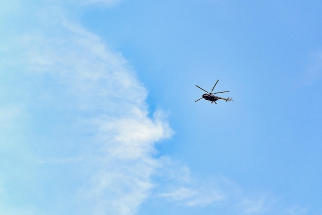 Latający helikopter na tle błękitnego nieba ze świerkowymi chmurami