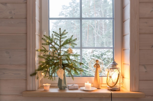 Latarnia bożonarodzeniowa anioł choinka i biały wystrój na oknie drewnianego domu