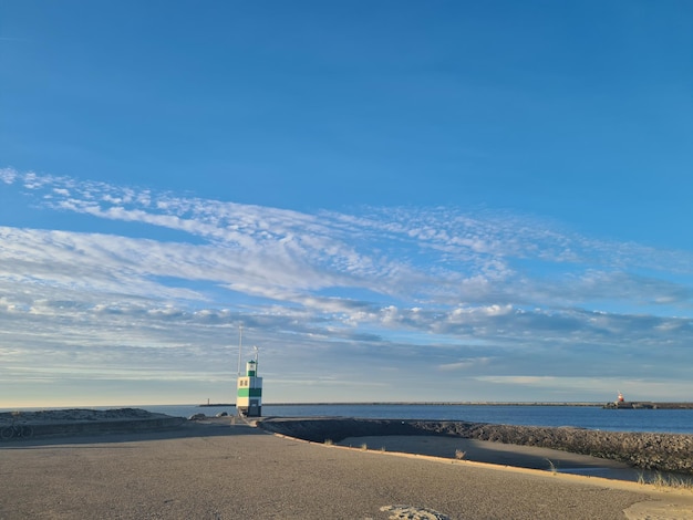 Latarnia morska na plaży z błękitnym niebem w tle.