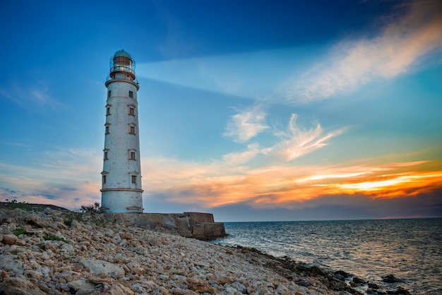 Latarnia morska w nocy emituje światło morskie. Seascape o zachodzie słońca